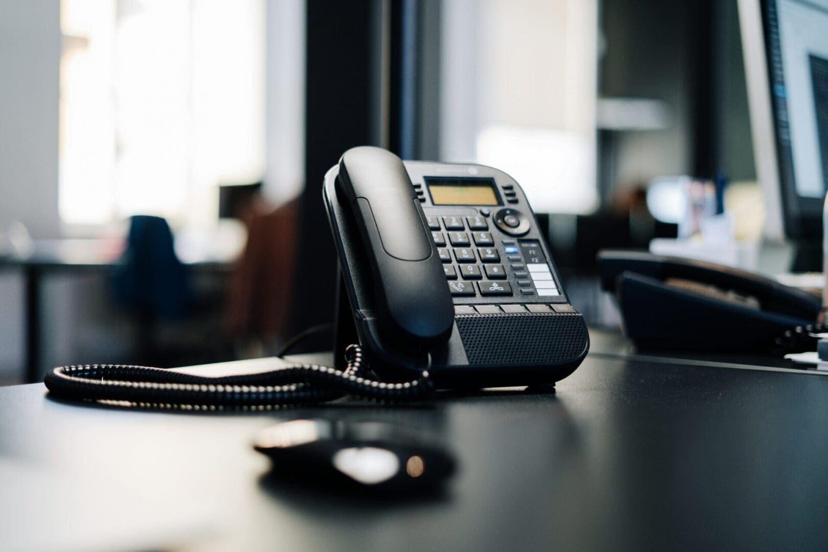 A black telephone sitting on top of a wooden table.