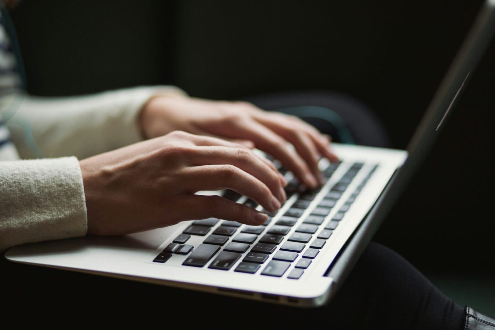 A person typing on a laptop keyboard.