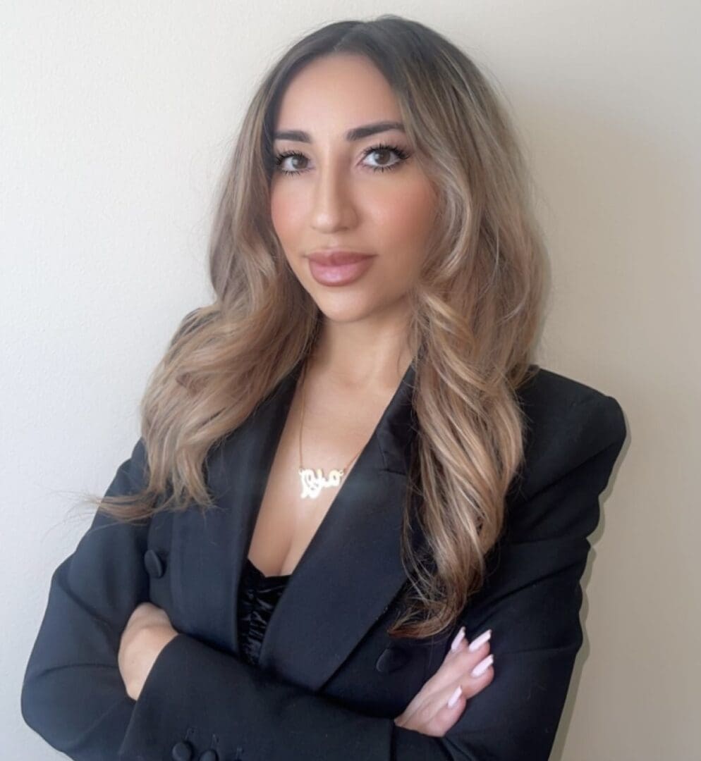 A woman in black jacket standing with her arms crossed.