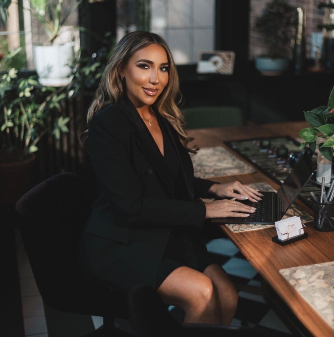 Woman in black blazer typing on laptop